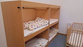Schlafraum - Das Bild zeigt den Schlafraum mit zwei Doppelstockbetten und einem Gitterbett